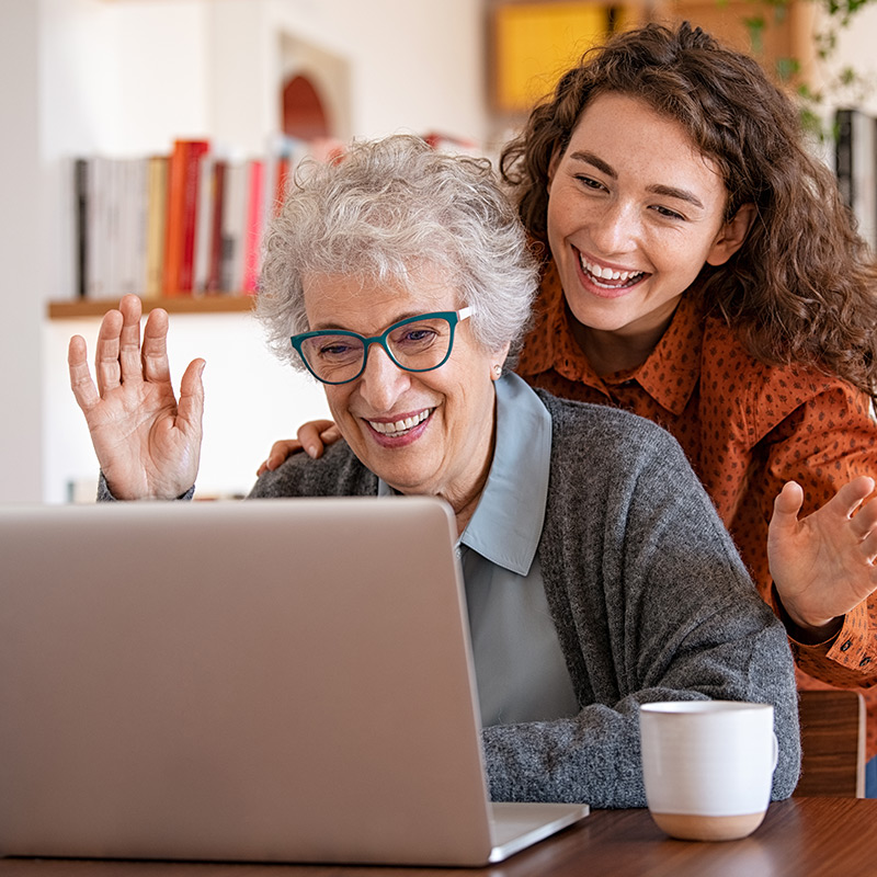 senior-woman-grandaughter-waving-laptop